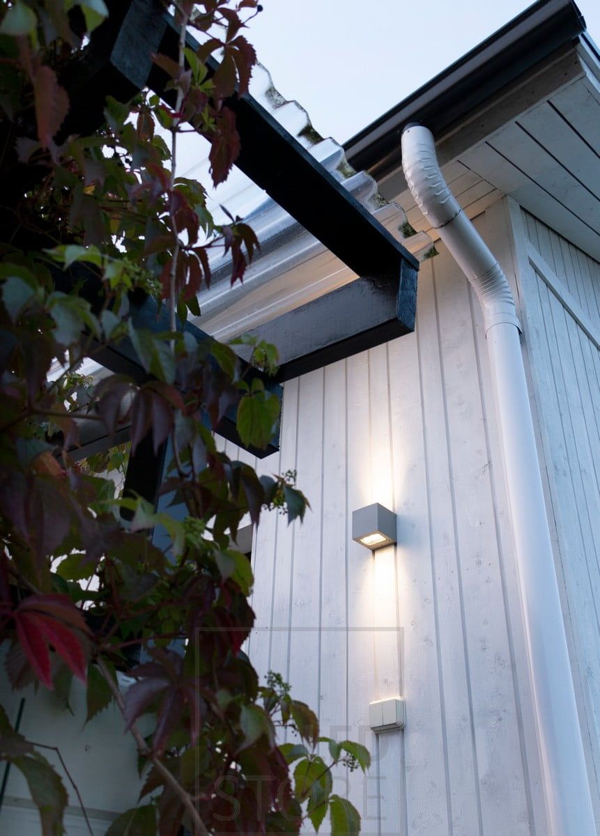 CUBIC OUT 2 on the wall of a house, illuminating in two directions with warm, atmospheric light.
